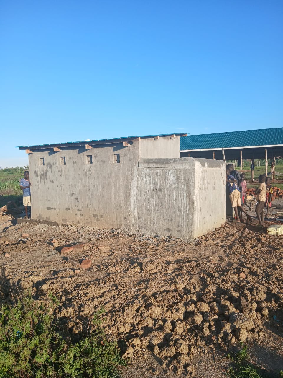 Children standing beside the newly completed latrine block at the Golden Mind Academy construction site in Ayilo.